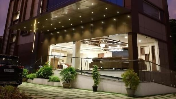A multi-story hotel with a glass facade, outdoor seating area, and a well-lit entrance. - GOLDEN STAR (Kollam)