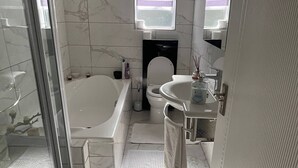 A bathroom with a bathtub, toilet, sink, and a shower area. - Room-a Peaceful and Scenic Area Designed (Cape Town)