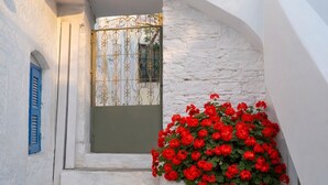 A white-washed building with a staircase leading to a door with a decorative metal gate. - Naxos Damarionas Retreat | Newly Renovated Cycladic House with Views (Damarionas)