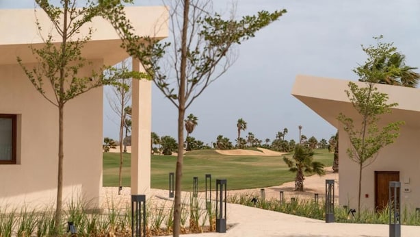 A modern building with a flat roof, a paved walkway, and a view of a golf course. - Good Days Habitat Soma Bay (Soma Bay)