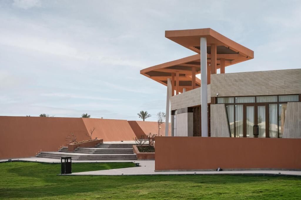 Un edificio moderno con un diseño arquitectónico singular, que destaca por una estructura sobresaliente y una escalera que conduce a la entrada.