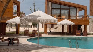 A poolside area with wooden structures, lounge chairs, and umbrellas. - Good Days Habitat Soma Bay (Soma Bay)