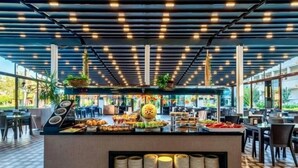 A buffet area with a central serving station, multiple seating arrangements, and a ceiling with exposed beams and lighting. - Hitit Marina Hotel & Bungalows (Alanya)