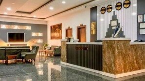 A reception area with a marble reception desk, a flat-screen TV, and a seating area with sofas and chairs. - Hitit Marina Hotel & Bungalows (Alanya)