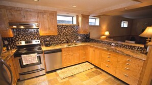 Una cocina con armarios de madera, estufa de acero inoxidable, lavavajillas y salpicadero de azulejos.