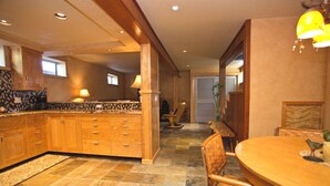 Una cocina con armarios de madera, una zona de comedor con una mesa redonda y una silla.