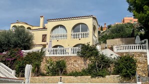 Ein mediterran gestaltetes Gebäude mit einer Stein-Fassade, Bogenfenstern und einem weißen Balkon.