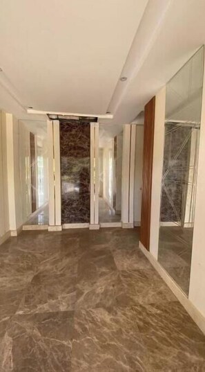 A spacious corridor with marble flooring, a central stone wall, and glass doors on the right. - Best Value Studio in Dreamland – Cozy, Quiet & Central (Giza Governorate)