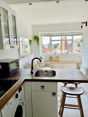 Eine Küche mit eingebauter Waschmaschine, einem Spülbecken und einem Fenster mit Blick auf eine Wohngegend.