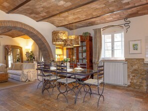 A dining area with a brick ceiling, a stone wall, and a large window. - Il Sogno Toscano by Interhome (Casale Marittimo)