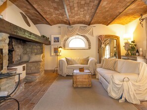 Ein gemütliches Wohnzimmer mit Kamin, einer Couch, einem Holztisch und einer Steinwand.