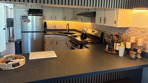 Eine moderne Küche mit einem Edelstahl-Kühlschrank, einem eingebauten Backofen und einer schwarzen Arbeitsplatte.