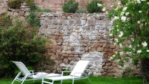 A stone wall with a white chair and a potted plant.