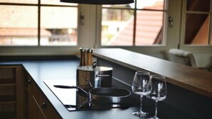 A kitchen counter with a stove, a pan, and two wine glasses.