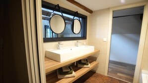 A bathroom with a white sink, two mirrors, and a wooden vanity.