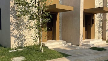 A modern building with a stone facade, a flat roof, and a paved entrance area.