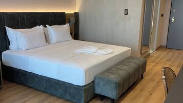 A modern bedroom with a large bed, bedside tables, a bench, and a wall-mounted light fixture.