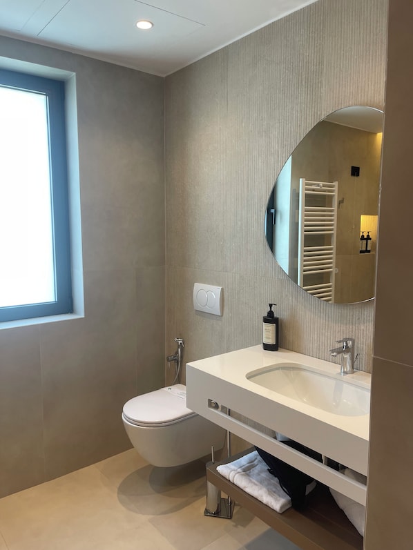Une salle de bain moderne avec des toilettes, un lavabo et un miroir.