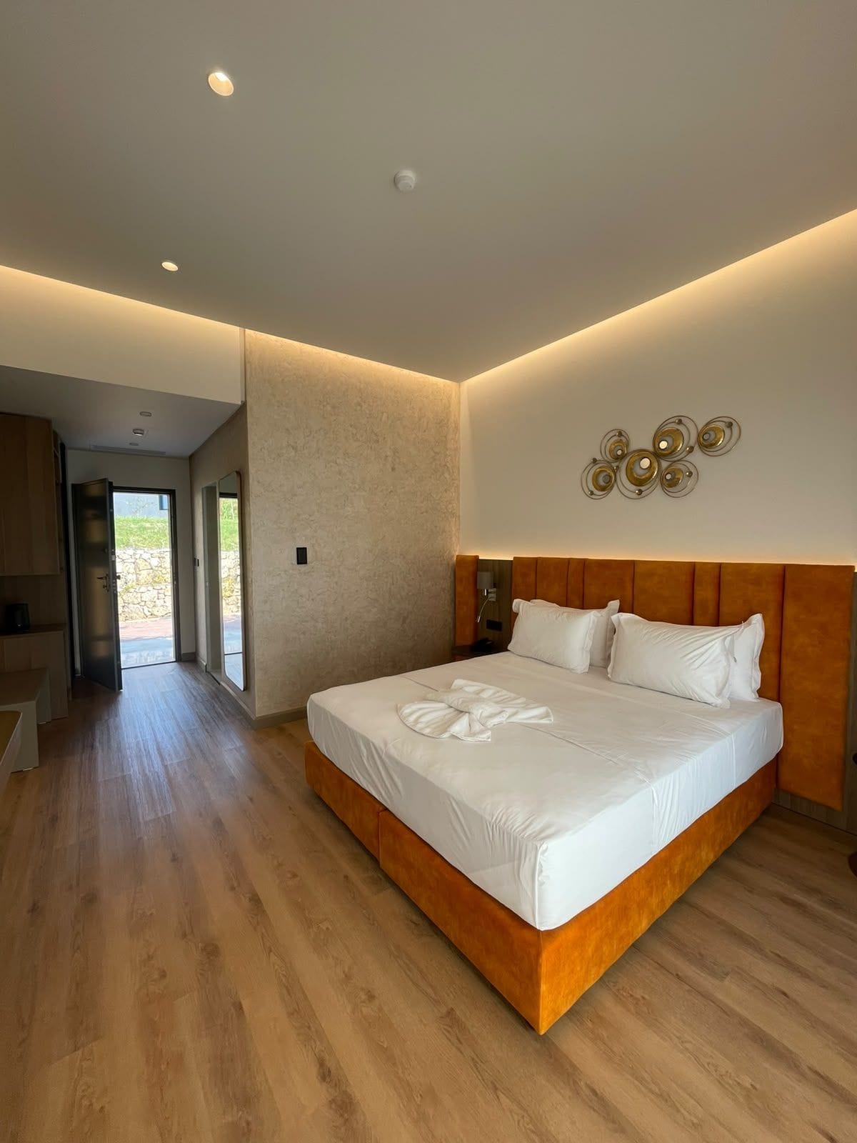 Ein modernes Schlafzimmer mit einem großen Bett, einem Holzkopfstück und einer Wandleuchte.