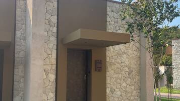 Un edificio moderno con fachada de piedra, entrada despejada y un letrero que indica 'Villa Persimmon Room 12'.