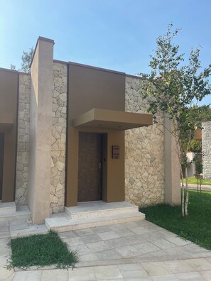 Un bâtiment moderne avec une façade en pierre, une entrée bien définie et une enseigne indiquant « Villa Persimmon, chambre 12 ».