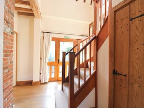 A wooden staircase leading to a door with a fire exit sign, a brick wall, and a wooden floor. - Six Apples (Braintree)