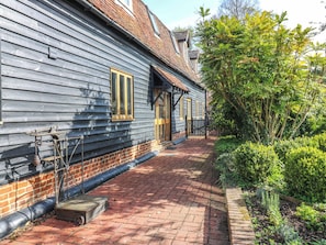 A traditional wooden building with a brick pathway and a garden. - Six Apples (Braintree)