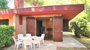 Um pátio com mesa e cadeiras, um muro de tijolos e uma porta de madeira.