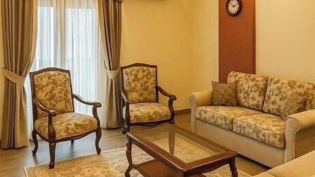 Una sala de estar con dos sillones, un sofá, una mesa de centro y una alfombra estampada.