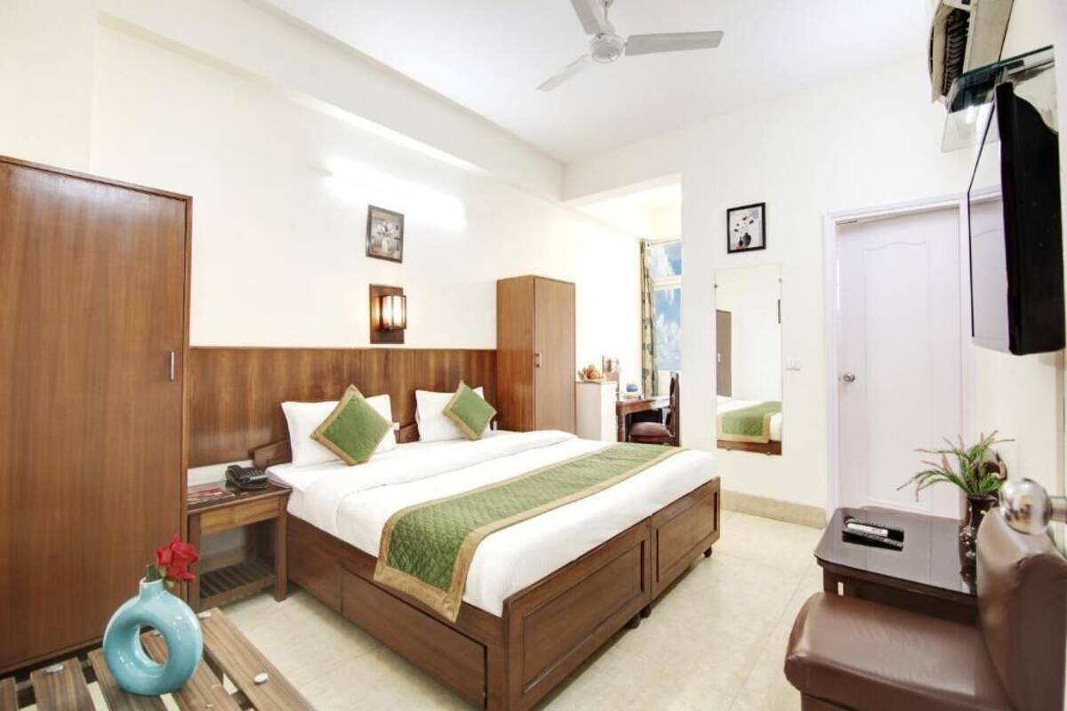 A hotel room with a bed, wardrobe, bedside table, and a television.