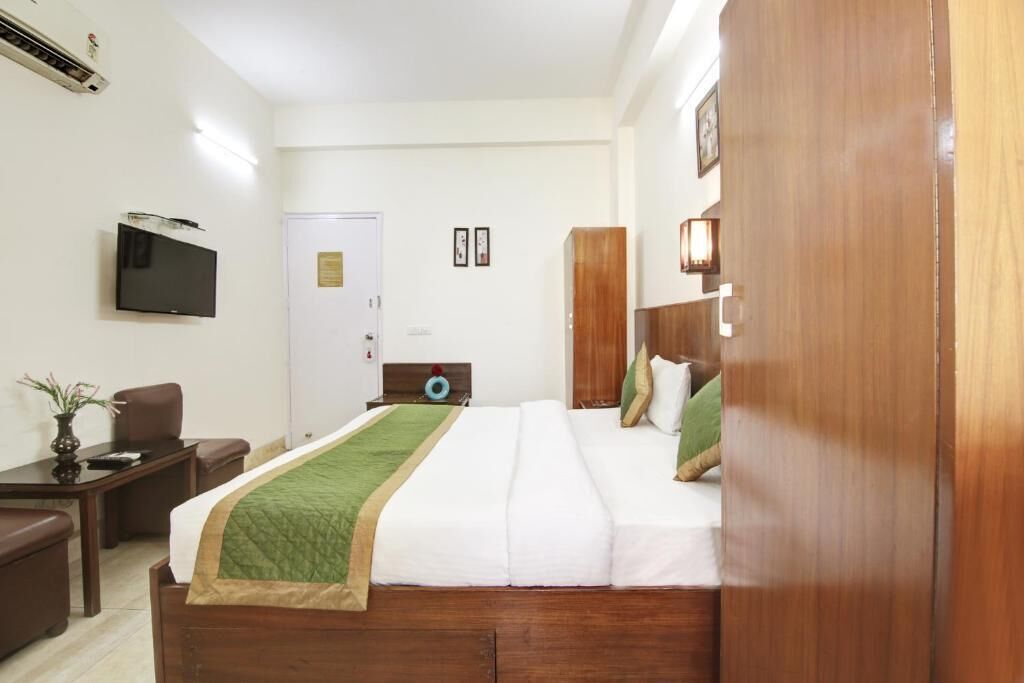 A hotel room with a bed, a desk, a chair, a television, and a wardrobe.