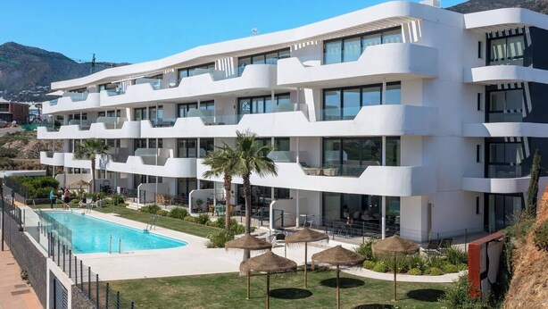 A multi-story hotel with a swimming pool, outdoor seating, and a view of the surrounding landscape. - Luxury 3-Bedroom Skyline Apartment in Higueron (Fuengirola)