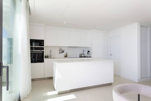 A modern kitchen with white cabinetry, a central island, and built-in appliances. - Luxury 3-Bedroom Skyline Apartment in Higueron (Fuengirola)
