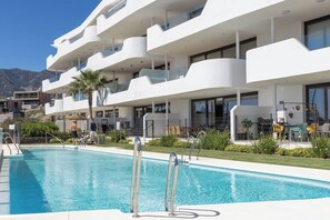 Ein modernes Hotel mit Schwimmbad, Außenbereich und Blick auf die Berge.