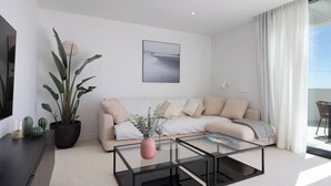 A modern living room with a sofa, a coffee table, and a potted plant. - Luxury 3-Bedroom Skyline Apartment in Higueron (Fuengirola)
