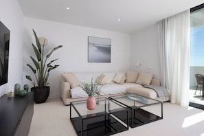 Ein modernes Wohnzimmer mit einer Couch, einem Couchtisch und einer Zimmerpflanze.