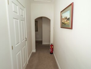 Ein Flur mit einer weißen Tür, einem gerahmten Bild an der Wand und einem Feuerlöscher.