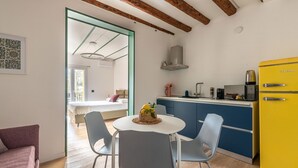Een moderne keuken met een gele koelkast, blauwe keukenkastjes en een eethoek met een ronde tafel en stoelen.