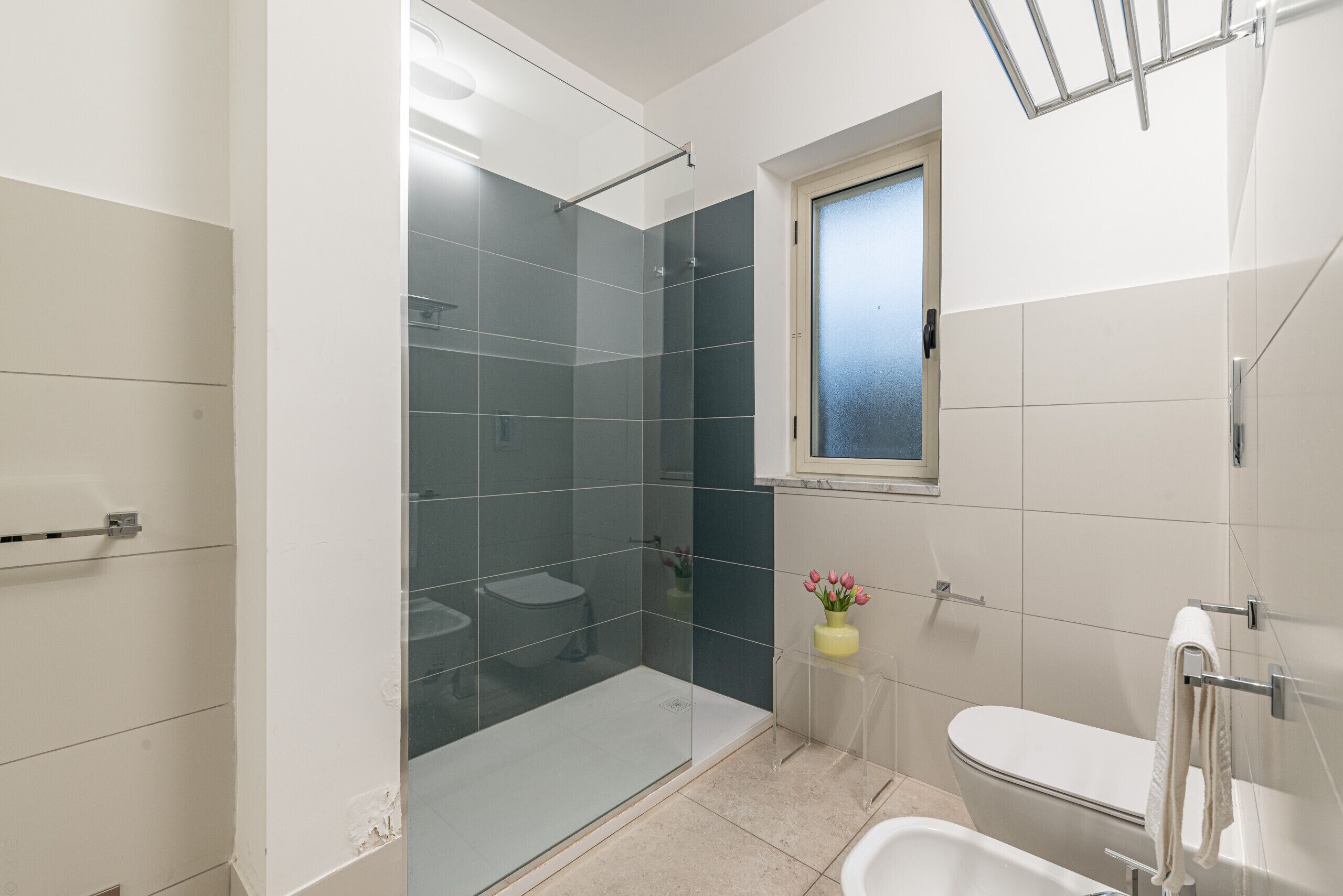 A modern bathroom with a glass shower enclosure, a toilet, and a bathtub.