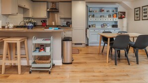A modern kitchen with a dining area, wooden flooring, and light blue cabinetry. - Number 7 Canalside (Skipton)