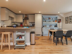 A modern kitchen with a dining area, wooden flooring, and light blue cabinetry. - Number 7 Canalside (Skipton)