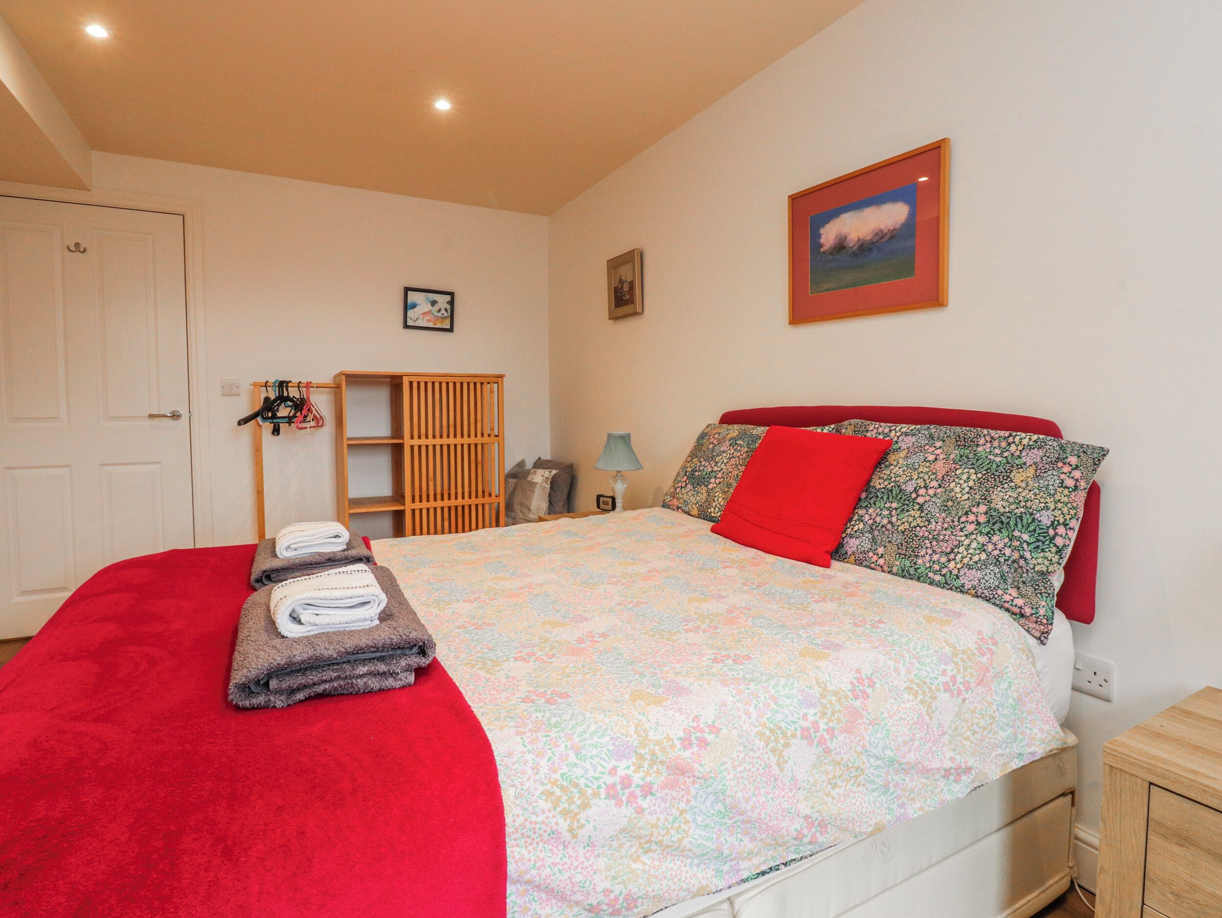 A bedroom with a bed, a wardrobe, a shelf unit, and a door.