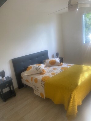 Une chambre à coucher avec un lit, une table de chevet, une lampe et une fenêtre.