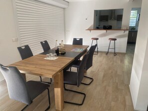 Ein Essbereich mit einem Holztisch, sechs Stühlen und einer Küche im Hintergrund.