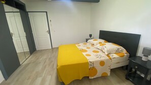 A bedroom with a bed, a nightstand, a bedside table, and a door. - LA POINTE DE VARIN VACATION RENTAL (Pointe-Noire)