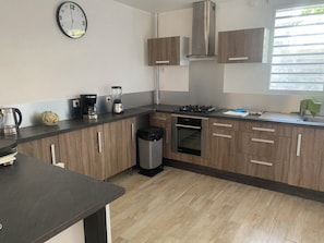 Eine moderne Küche mit Holzschränken, einem Gasherd, einem Backofen, einer Kaffeemaschine und einem Mixer.
