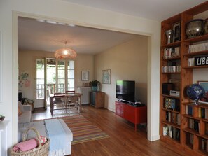 Ein Wohnzimmer mit Fernseher, Bücherregal und Essbereich.