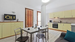 Una cocina compacta con comedor, cafetera y televisor en la pared.