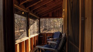 A wooden cabin with a porch, two chairs, and a table.