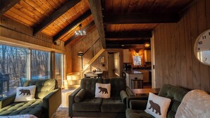 A cozy cabin interior with a wooden ceiling, a dining area, and a kitchen.